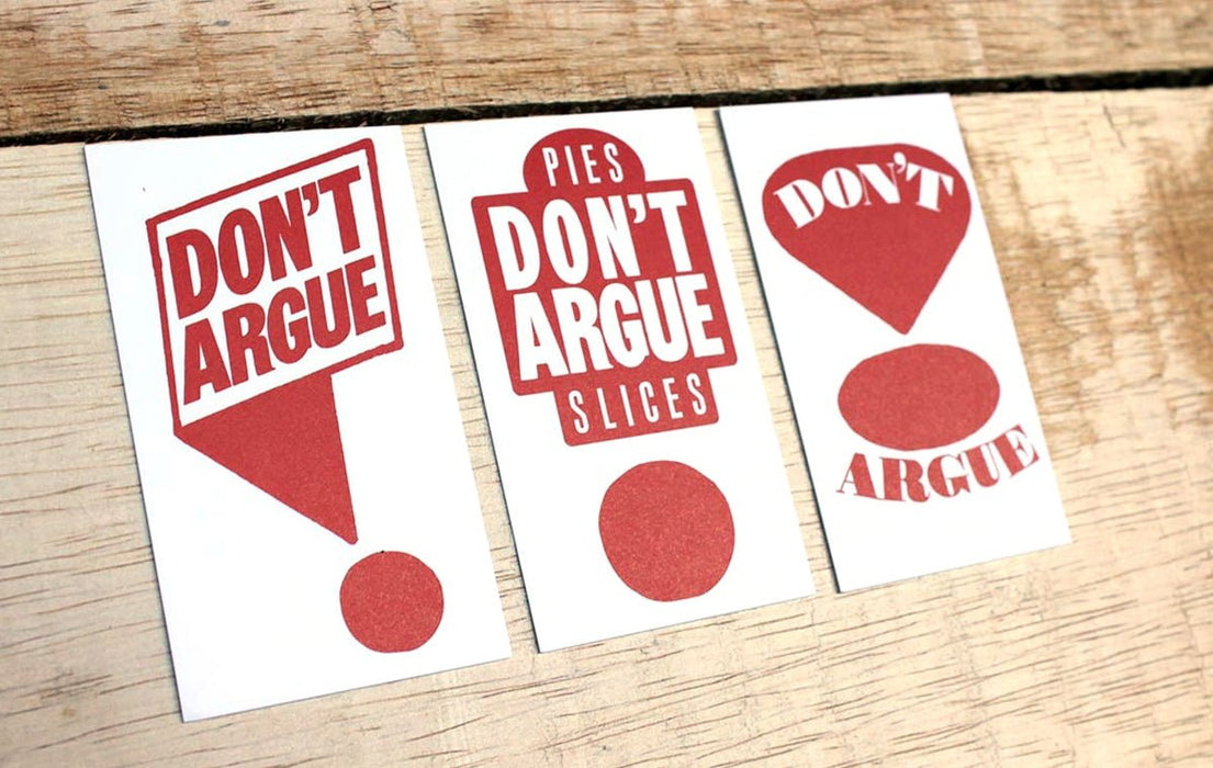 Custom 14pt uncoated business cards with red Don't Argue graphic text and pie slice illustrations on a wood background