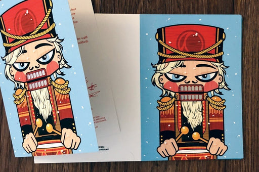 Open 7x5 folded holiday greeting card sample on 19pt suede stock showing printed interior and nutcracker cover with 3D raised iridescent foil accents