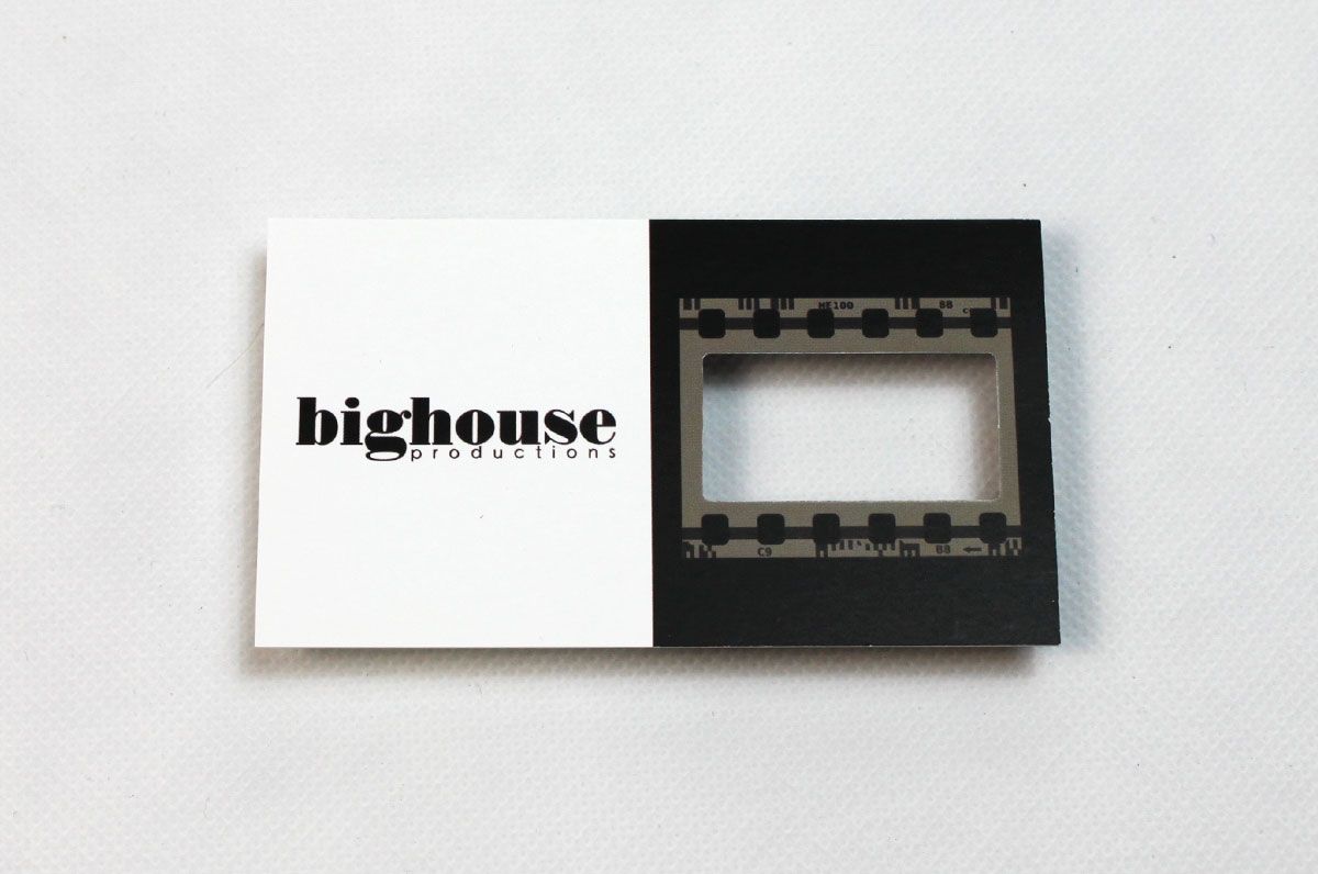 Custom shape die cut business card for Bighouse Production on our Silk Laminated 16pt Stock | Left side of the card is white with the company name in black | Right side of card is black with a grey film strip centered on that half | the middle of the film strip where the picture would usually be is cut out so you can look through | Clubcard Printing USA